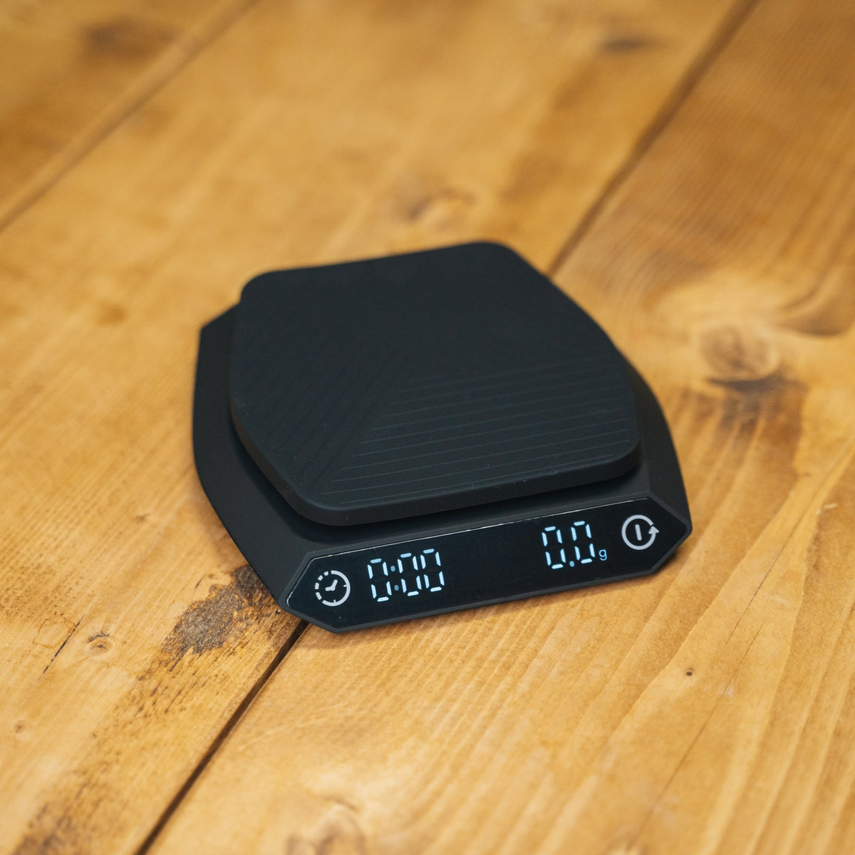 A black digital kitchen scale with a responsive sensor and digital display, placed on a wooden surface.