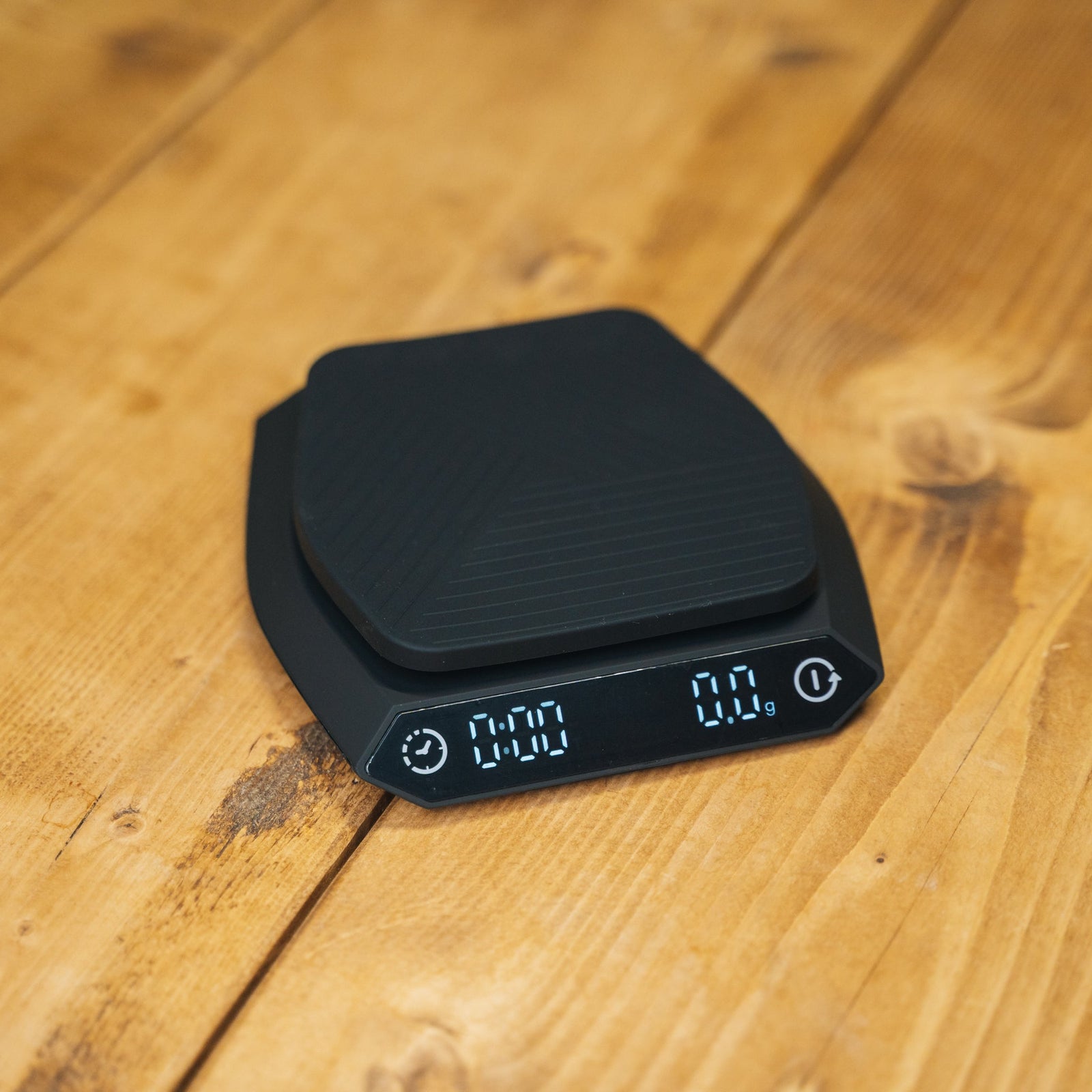 A black digital kitchen scale with a responsive sensor and digital display, placed on a wooden surface.