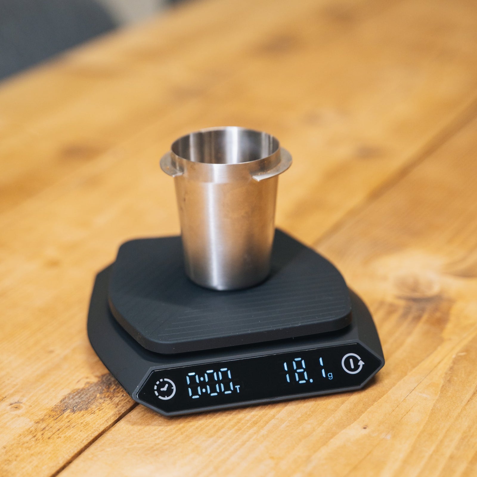 A black digital kitchen scale with a responsive sensor and digital display, placed on a wooden surface.